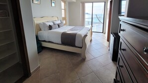 Une chambre à coucher comprenant un lit, une commode, un ventilateur de plafond et une vue sur l’extérieur grâce à une grande fenêtre.