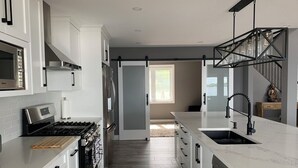Una cocina moderna con armarios blancos, una estufa de acero inoxidable y una isla grande con un fregadero.