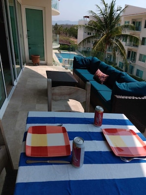 Un balcon avec une table dressée pour deux personnes, agrémenté de nappes à rayures et d’une canette de soda.