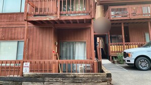 A two-story wooden building with balconies, a 'No Parking Any Time' sign, and a parked truck. - Walk To Ski Lifts! W/D, WiFi, Kitchen, Skylights (Angel Fire)