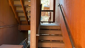 A wooden staircase with metal handrails, leading to an upper level. - Walk To Ski Lifts! W/D, WiFi, Kitchen, Skylights (Angel Fire)