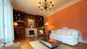 A living room with a fireplace, a white sofa, a coffee table, and a bookshelf. - Villa ANNE-MARIE - BAYONNE (BAYONNE)