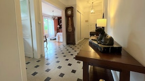 A hallway with a checkered floor, a wooden bench with a statue, a clock, and a lamp. - Villa ANNE-MARIE - BAYONNE (BAYONNE)