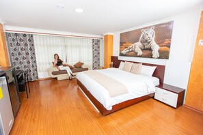 A hotel room with a large bed, a desk, and a chair. There is a painting of a tiger on the wall. - Hotel La Kapital (Ambato)