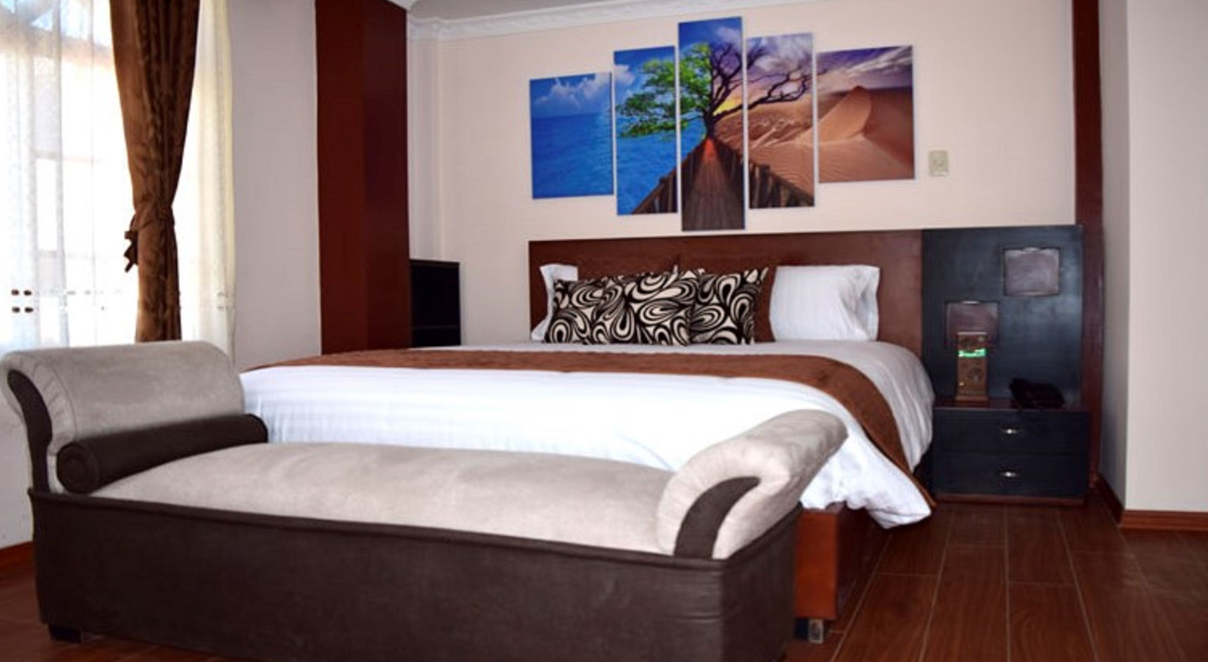 A spacious bedroom with a large bed, a bedside table, and a wall-mounted TV.