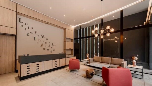 A modern living room with a sofa, red chairs, a coffee table, and a large wall with alphabet letters.