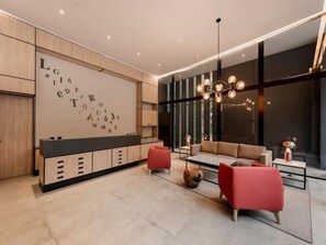 Een moderne woonkamer met een bank, rode stoelen, een salontafel en een grote muur met letters.