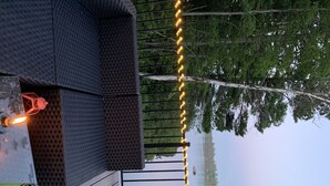 A wooden deck with a railing, a lantern, and string lights. - 2 Bedroom Camper with Rooftop Boat House Deck (Gwinn)
