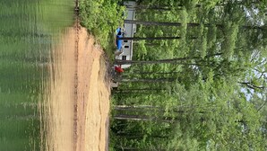 A campsite with tents and a vehicle near a forested area by a lake. - 2 Bedroom Camper with Rooftop Boat House Deck (Gwinn)