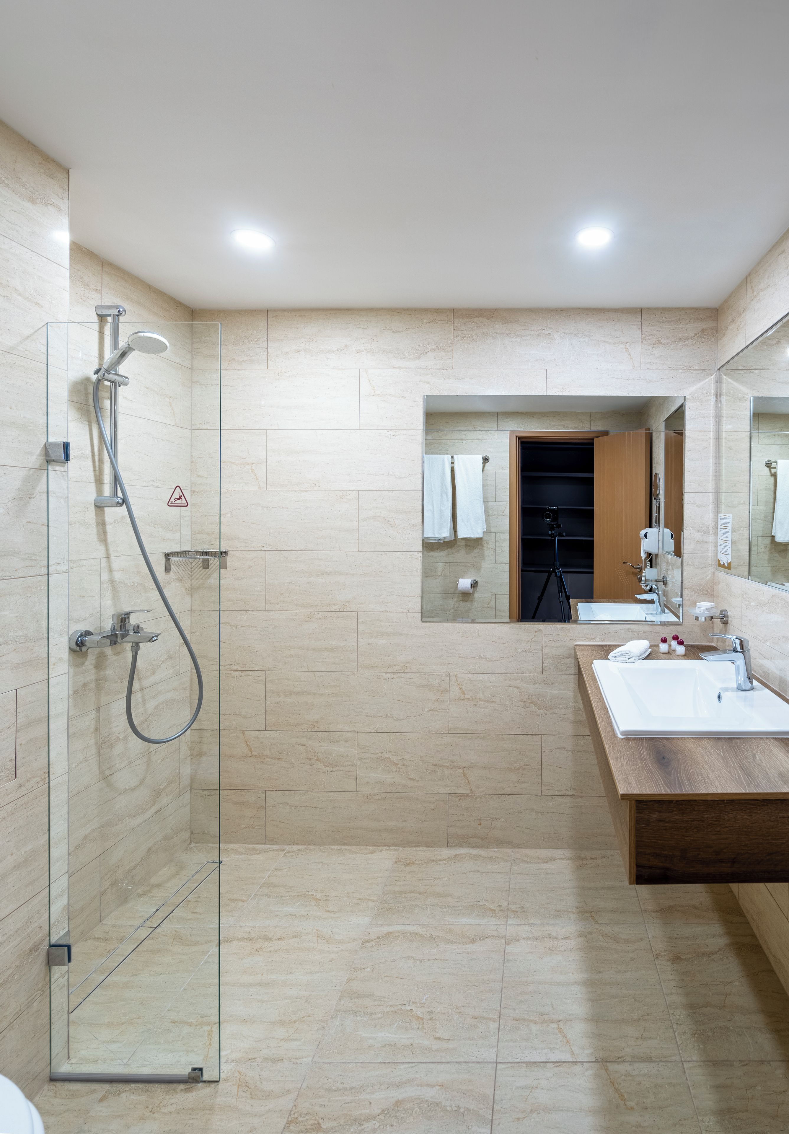 Un baño moderno con ducha de vidrio, tocador de madera y un espejo grande.