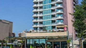 A hotel with a pool area, multiple balconies, and a clear sky.
