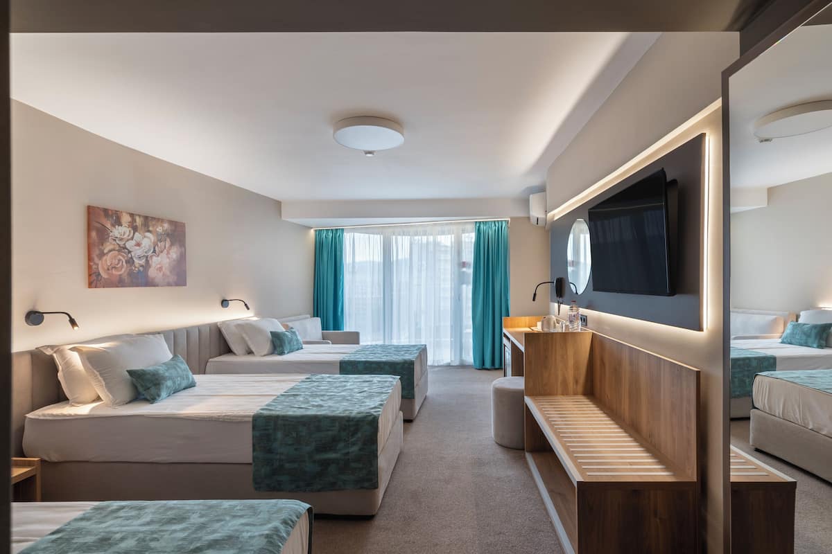 Una habitación de hotel con dos camas, un banco de madera, un televisor y un espejo grande.