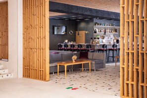 Un espace bar moderne comprenant un comptoir, des sièges et un téléviseur.