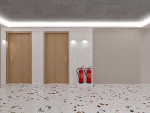 Quarto com duas portas de madeira, parede branca com o número 15 e um extintor de incêndio.