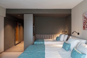 Una camera d'hotel con un letto grande, un'area salotto e una porta che dà su un corridoio.