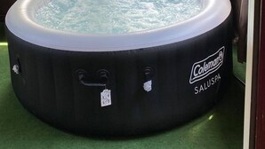A hot tub labeled 'Coleman Saluspa' under a pergola with curtains, surrounded by greenery. - Hot Tub, Fire Ring, Charcoal Grill, Hocking Hills, Buckeye Lake, Legend Valley (Somerset)
