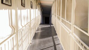 A covered corridor with white railings and a tiled floor, leading to a dark doorway. - Hotel Acuario  (Ocotlan)
