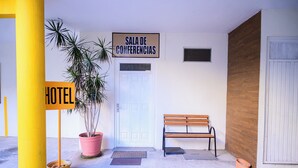 A hotel entrance with a sign for the conference room, a bench, and a potted plant. - Hotel Acuario  (Ocotlan)