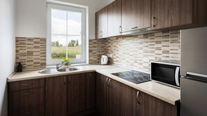 A modern kitchen with wooden cabinets, a large window, a sink, a kettle, a microwave, and a refrigerator. - 2 House Between two lakes (Vilnius)