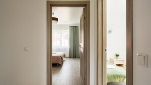 A narrow hallway leading to a bedroom with a bed, a bedside table, and a nightstand. - 2 House Between two lakes (Vilnius)