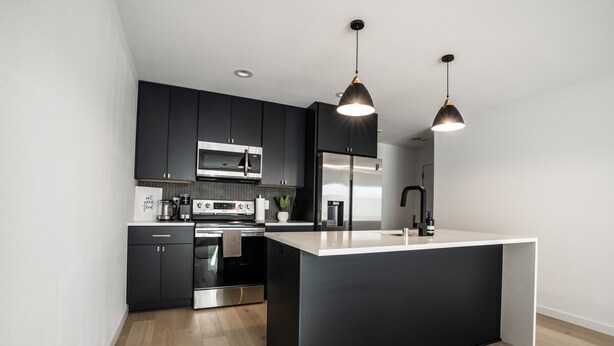 Een moderne keuken met zwarte kastjes, roestvrijstalen apparatuur en een groot eiland.