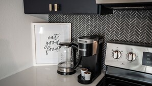 Een keuken met een koffiezetapparaat, een lijst in een fotolijstje en een fornuis.