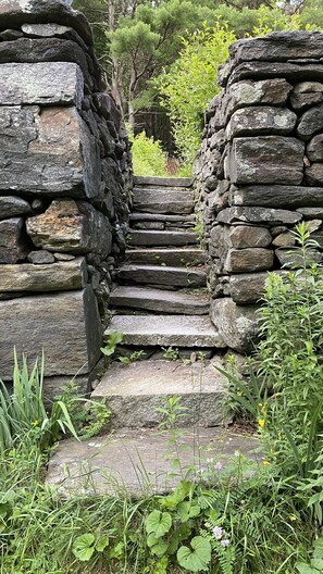 A stone staircase leading up to a stone structure surrounded by greenery.