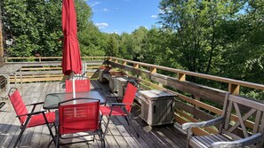 A wooden deck with outdoor seating, including tables and chairs, and a wooden railing. - Mountain Top Escape (Putney)