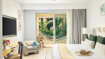 A hotel room with a bed, a desk with a chair, a TV, and a view of a garden through a sliding door.