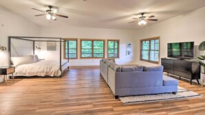 Ein geräumiges Schlafzimmer mit Himmelbett, grauem Sofa und Fernseher.