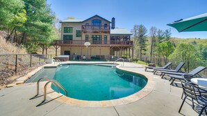 Ein Swimmingpool mit Liegefläche, Liegestühlen und einem Gebäude mit Balkon im Hintergrund.