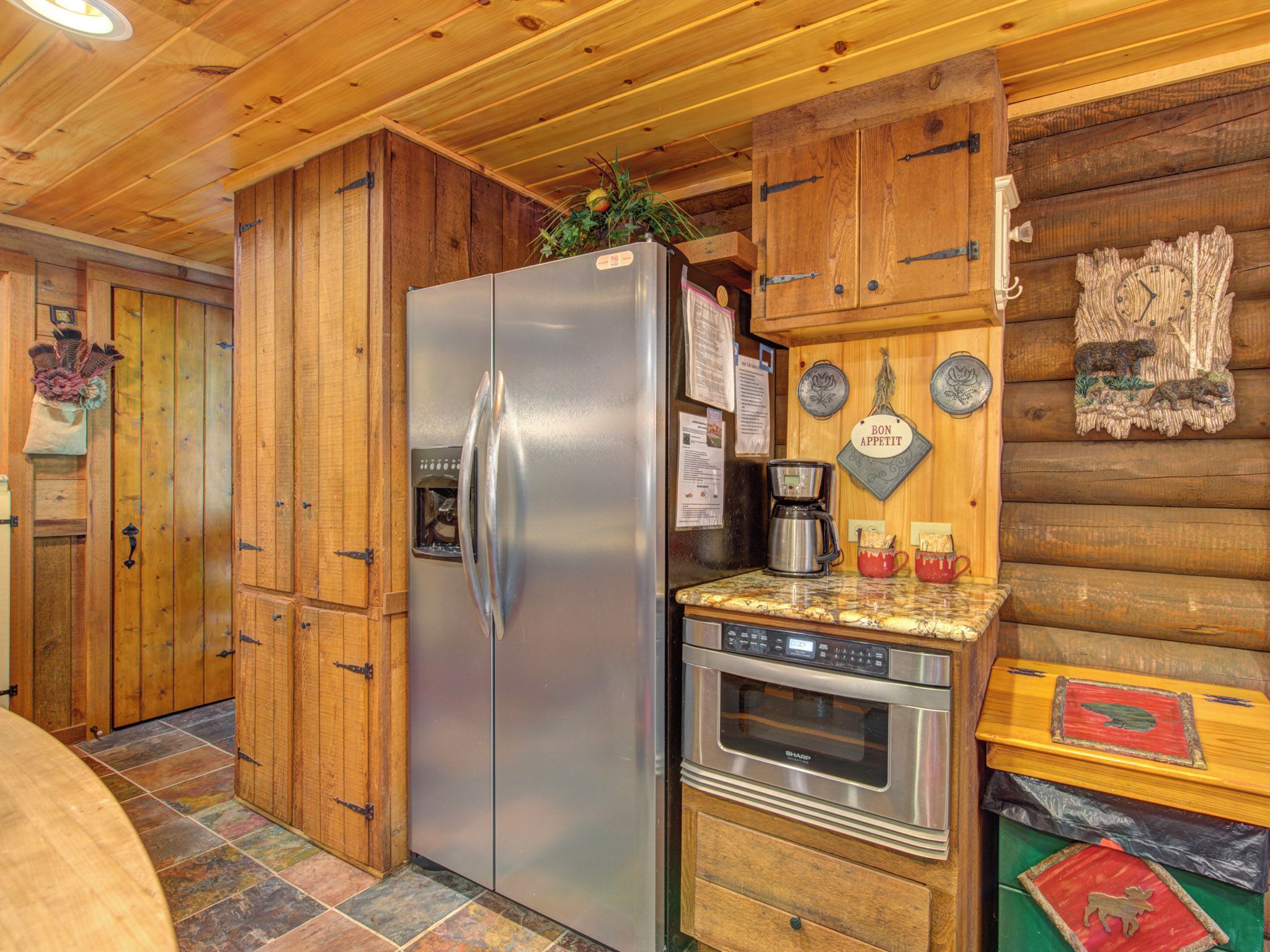 Una cocina con armarios de madera, un refrigerador de acero inoxidable, una cafetera y una estufa.