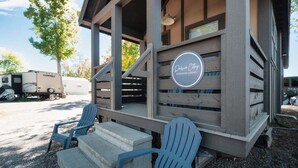 A rustic cabin with a porch, Adirondack chairs, and a sign that reads 'Dakic Cottages.' - Dockside at River Rocks Landing (Gadsden)
