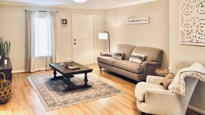 Una sala de estar con sofá, sillón, mesa de centro y lámpara.
