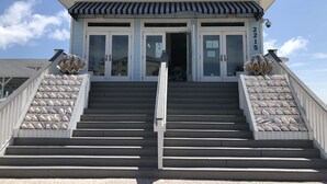 Un edificio con una escalera que lleva a una puerta con un cartel de 'Help Wanted', flanqueado por elementos decorativos.
