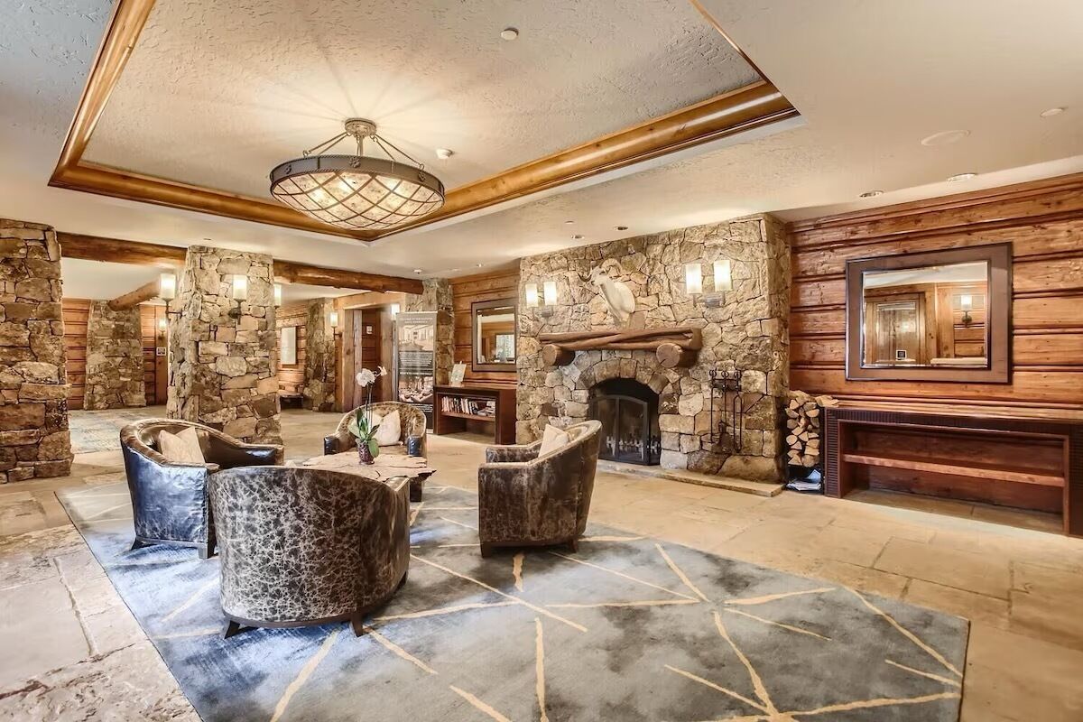 A spacious lobby with stone walls, a fireplace, and leather armchairs.