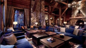 A cozy log cabin interior with a stone fireplace, wooden beams, and plush seating. - Ritz-Carlton Beaver Creek -- LUXURIOUS-2BR,2Bath, SLOPESIDE & inside hotel (Beaver Creek)
