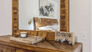 A wooden vanity with a mirror, a candle, and a sign that reads "Climb Mountain Every Mountain."