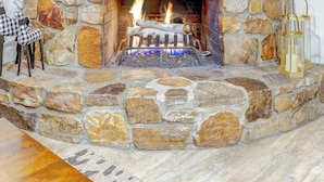A stone fireplace with a framed deer head decoration, a checkered stool, and a lantern.