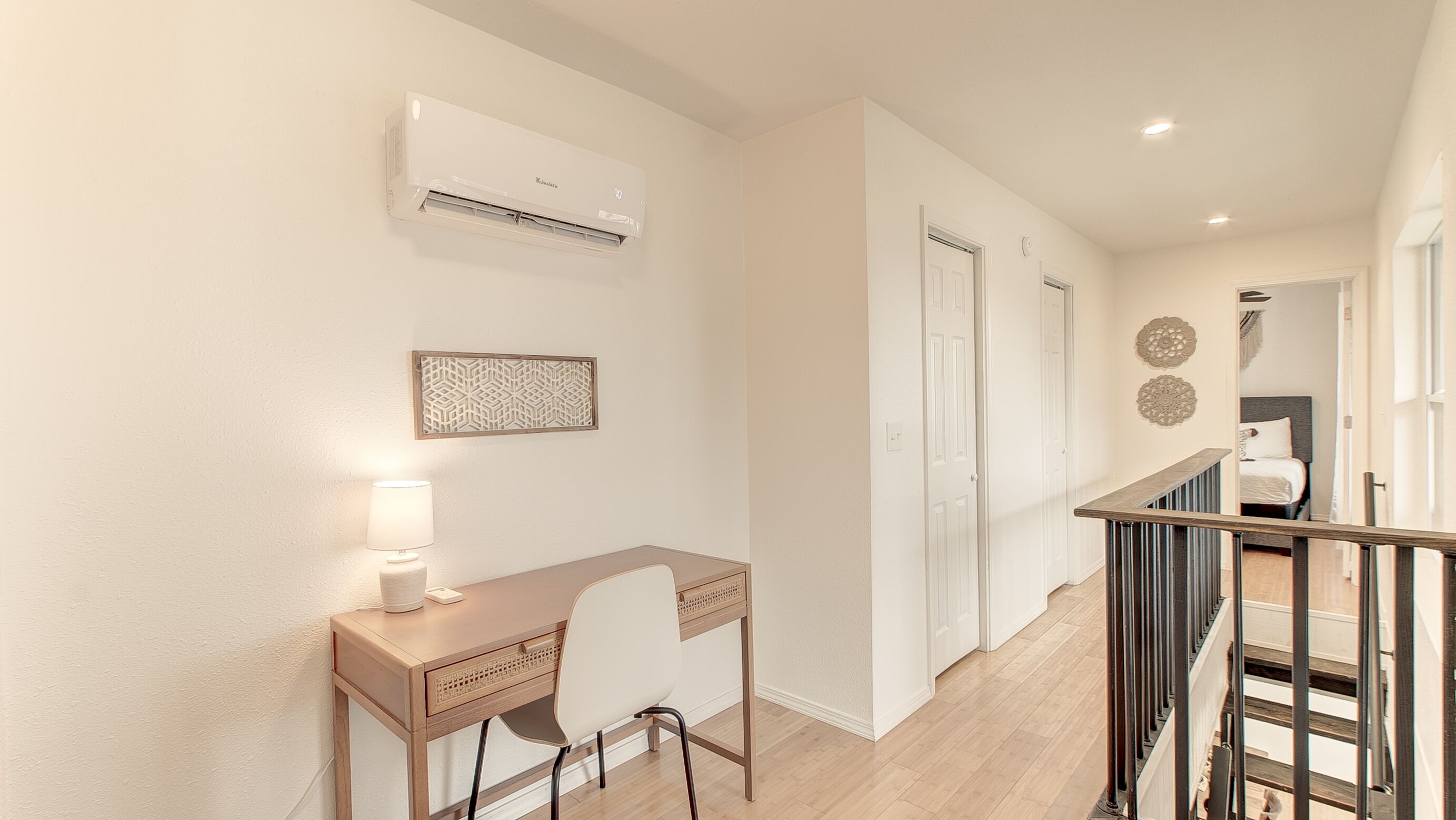A modern home office with a desk, chair, and an air conditioning unit on the wall.