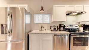 A modern kitchen with stainless steel appliances, a built-in oven, a coffee maker, and a dishwasher.
