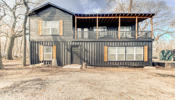 Une maison à deux étages avec un balcon, une porte d’entrée et un garage.