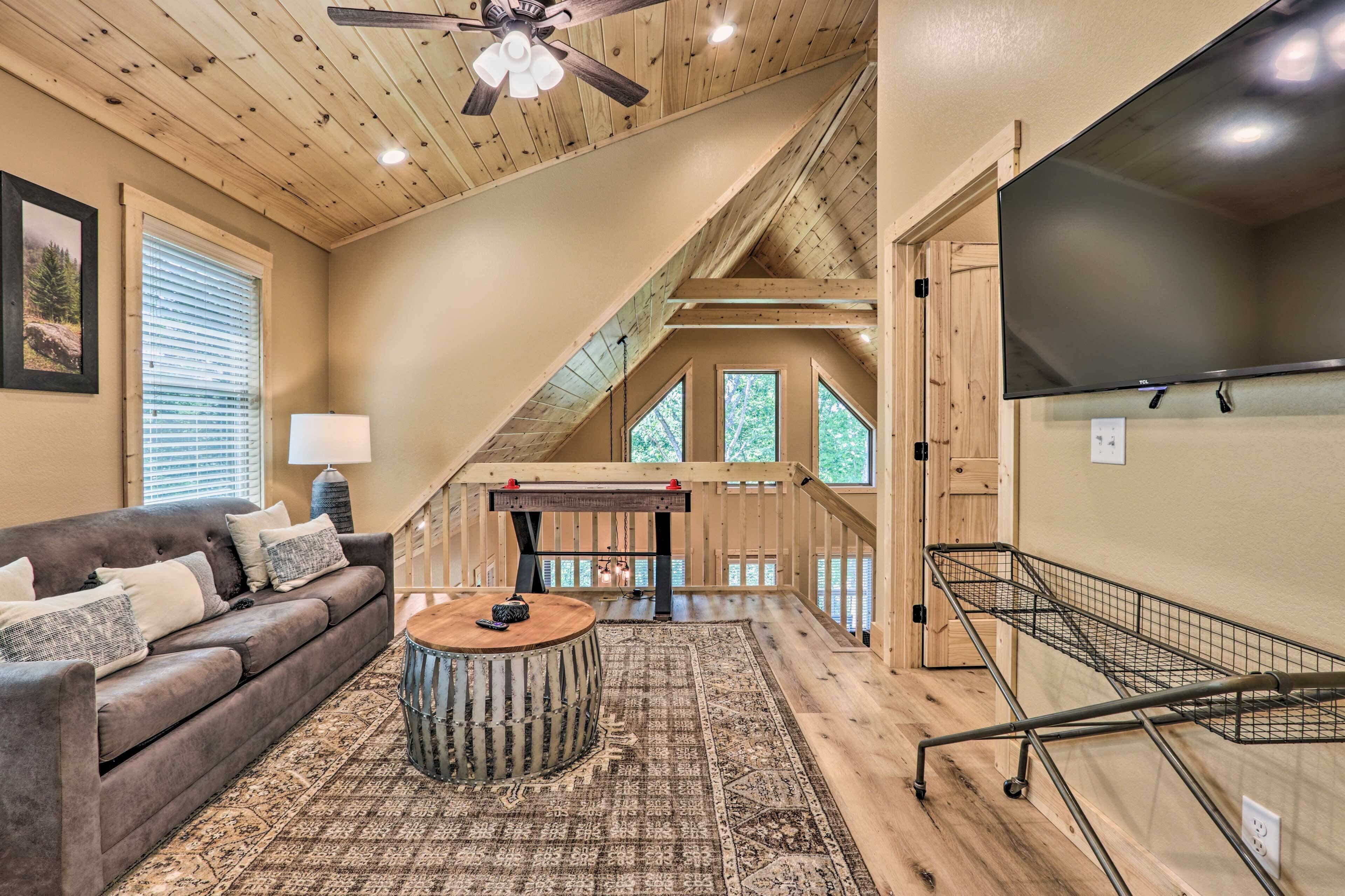 Une pièce confortable de style loft, avec un plafond en bois, une grande fenêtre, un canapé, une table basse et un téléviseur.