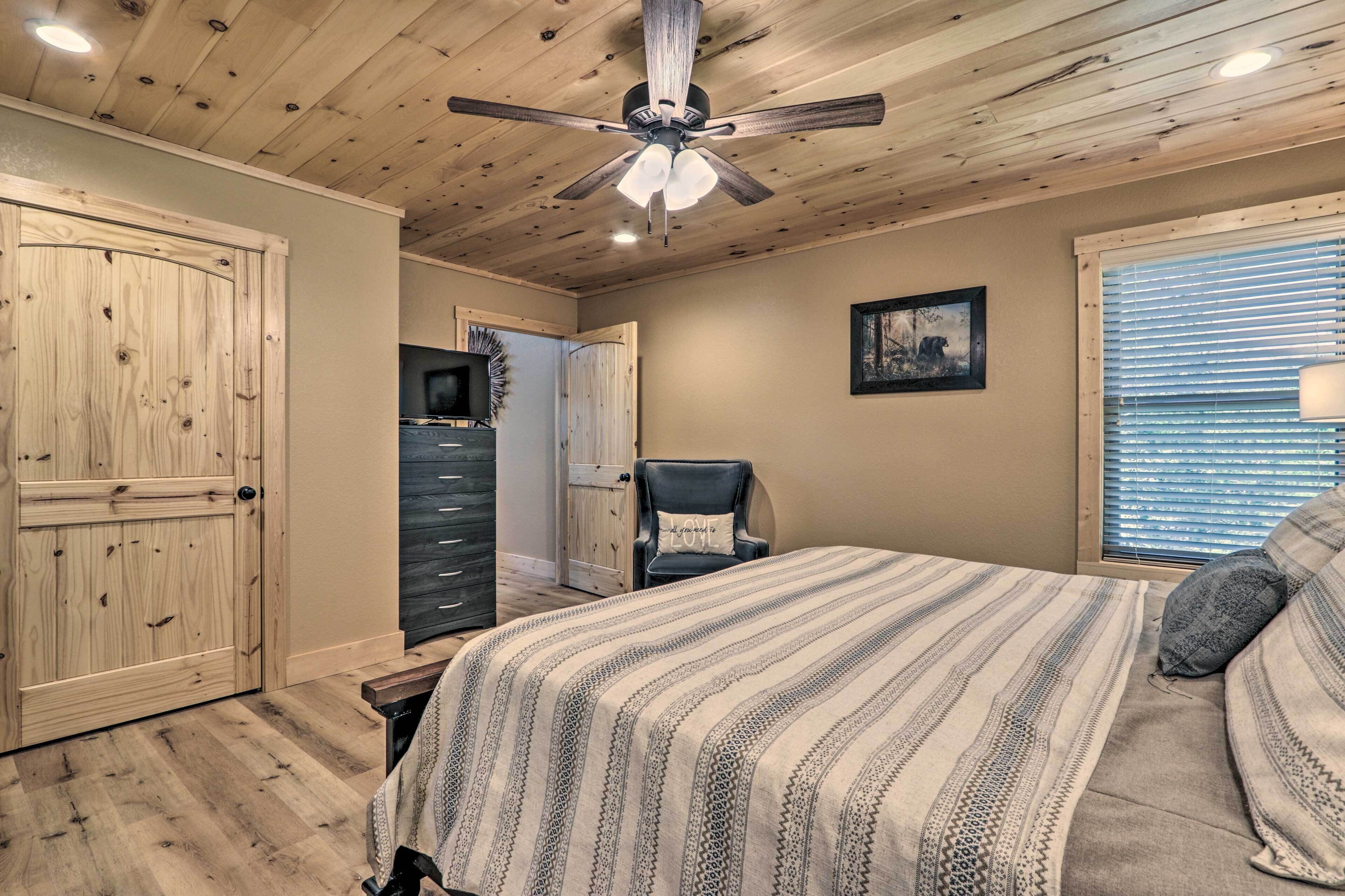 A bedroom with a bed, a ceiling fan, a dresser, a chair, and a window with blinds.
