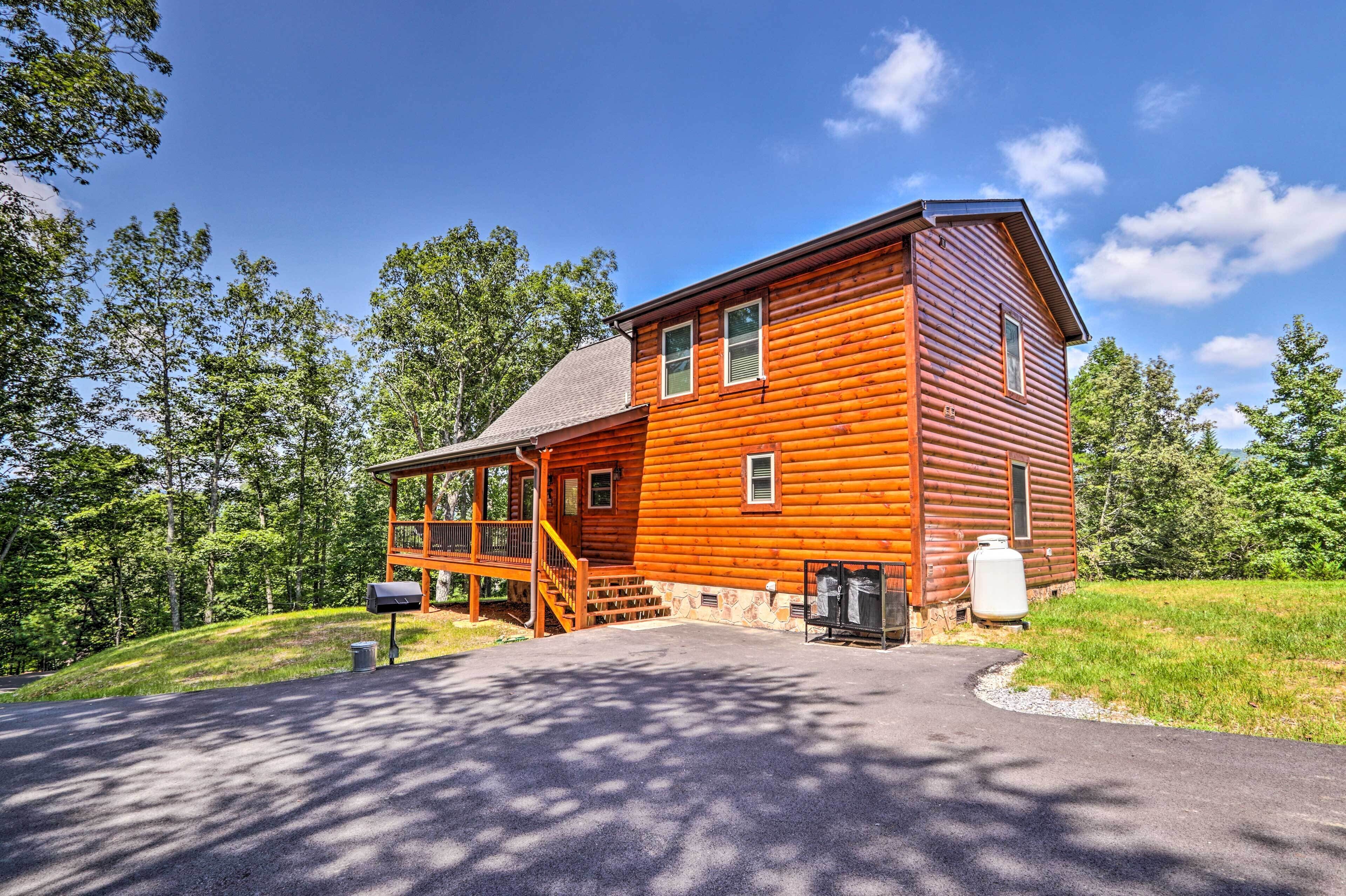 Une cabane en rondins dotée d’une véranda, d’une entrée principale et d’une petite dépendance attenante.