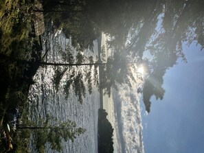 Een kalm meer met weerspiegelingen van bomen en een heldere lucht.