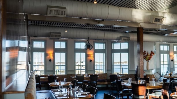 A restaurant with large windows, high ceilings, and a view of the water. Tables are set with glasses and cutlery. - Getaway Country Cottage - Entire house - Unique Find /Outdoor Decking           (New Bern)