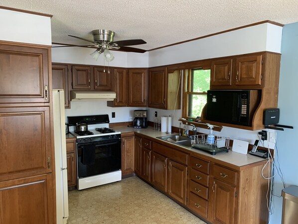 A kitchen with wooden cabinets, a stove, a microwave, and a ceiling fan. - Highland Lake Waterfront home perfect for family, fun, outdoors, and S’Mores! (Washington)
