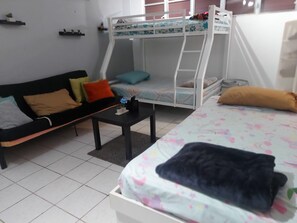 A room with a bunk bed, a sofa, a coffee table, and a bed with a floral bedspread.