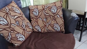 Uma cadeira preta com almofada marrom e almofadas estampadas com flores.